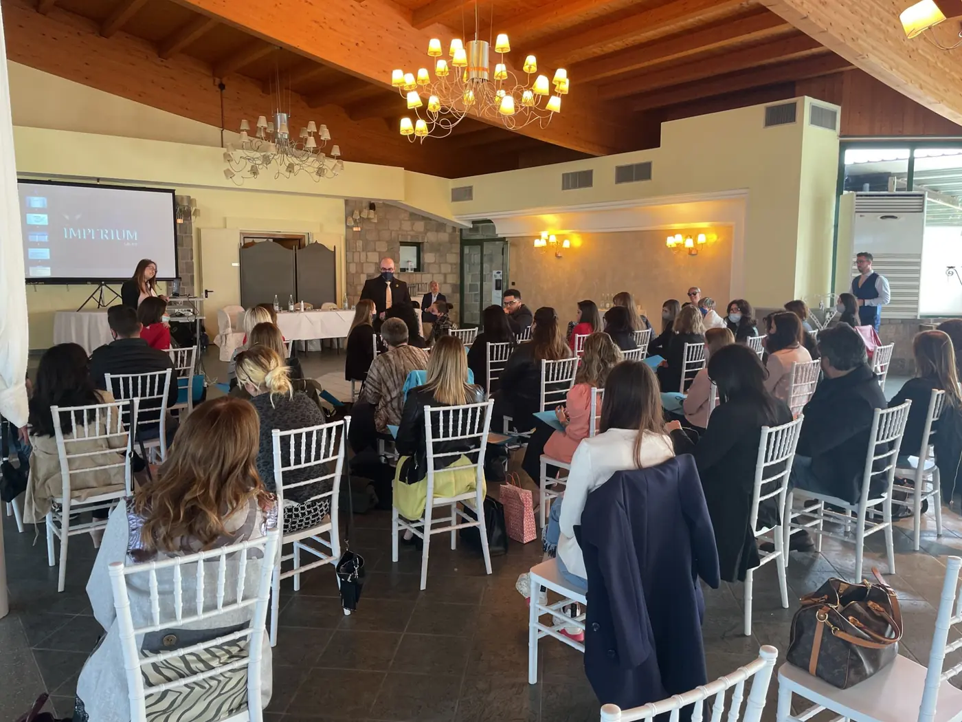 Evento aziendale in una sala con il pubblico seduto e lo schermo con il logo Imperium Group